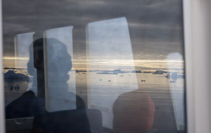 Bootsfahrt durch die Diskobucht mit Blick durch das Bootsfenster, Spiegelung von Bergen und Personen während einer Fotoreise nach Grönland