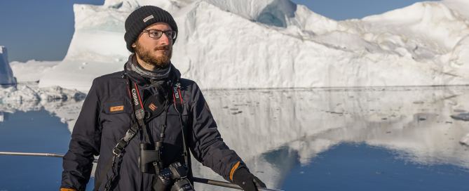 Teilnehmer einer Grönland-Fotoreise auf einem Boot vor großen Eisbergen in der Diskobucht