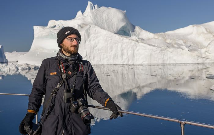 Teilnehmer einer Grönland-Fotoreise auf einem Boot vor großen Eisbergen in der Diskobucht