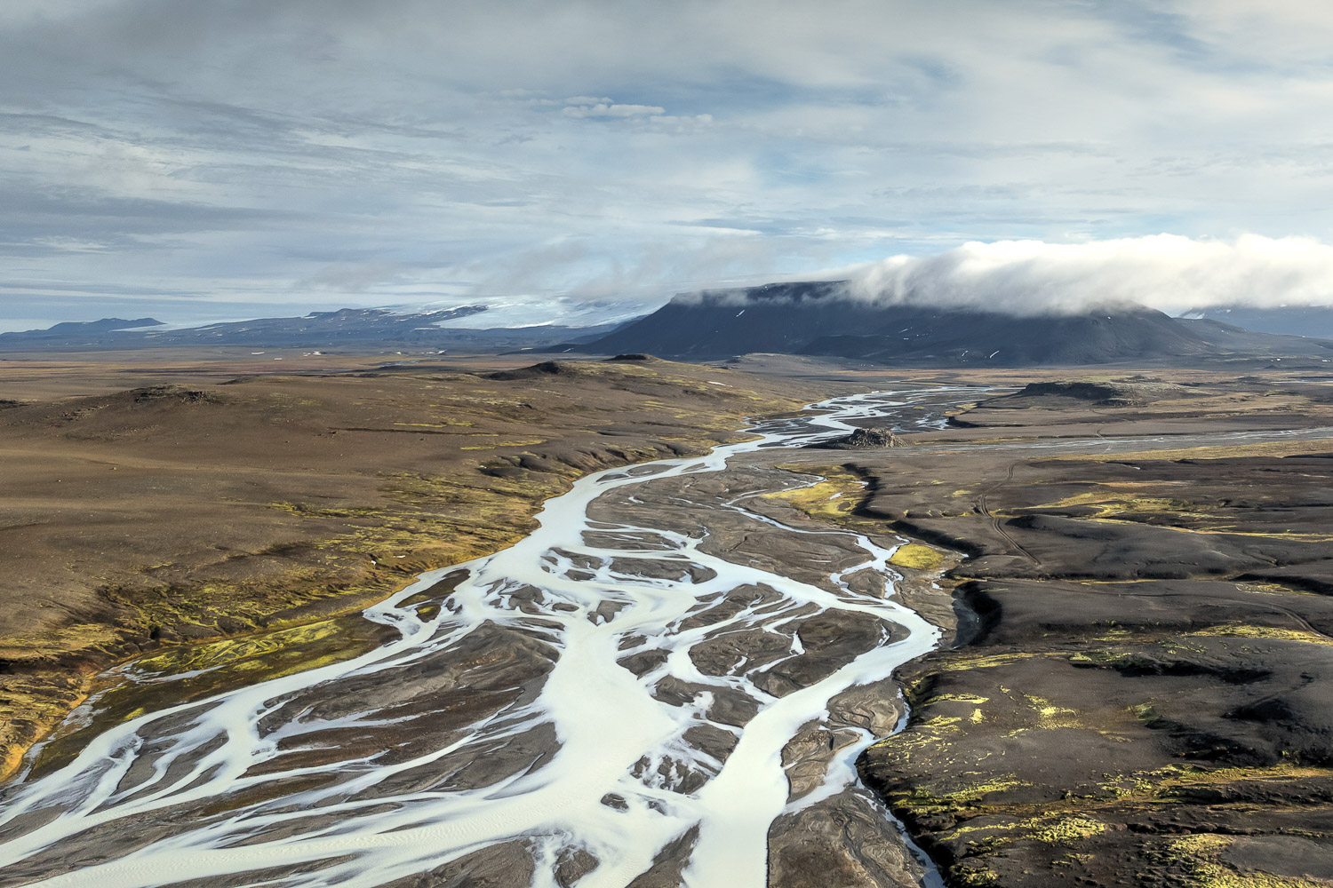 Islands zentrales Hochland – Kerlingarfjöll und Langjökull Verzweigter Gletscherfluss im zentralen Hochland bei Kerlingarfjöll, dahinter der Langjökull-Gletscher und wolkenverhangene Berge.