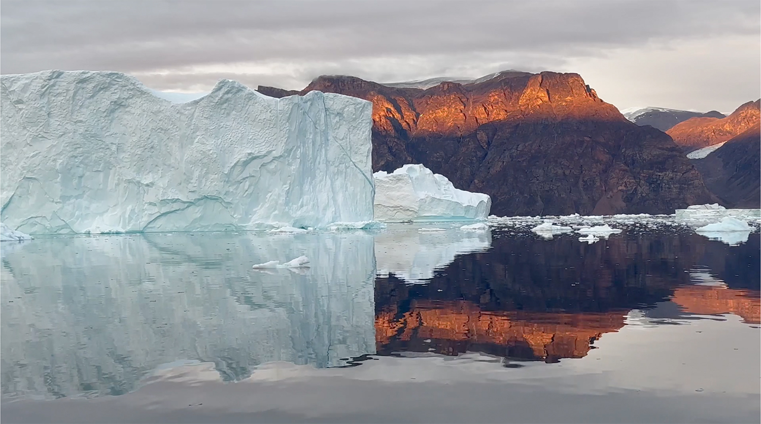 Rote Felswände und Eisberge im Abendlicht des Rødefjord in Grönland