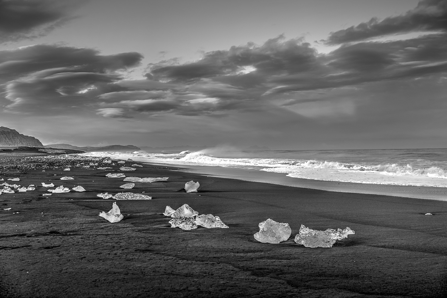 Diamond Beach Island – Eisdiamanten am schwarzen Strand (S/W) Schwarzweißfoto vom Diamond Beach in Island: Eisbrocken wie „Diamanten“ auf schwarzem Sand, Brandung und dramatische Wolken.