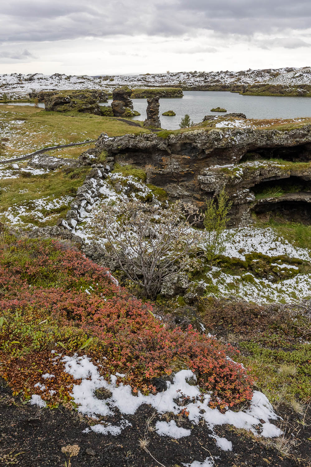 Lavaformationen und kleine Seen in der Mývatn-Region in Nordisland mit Herbstfarben und erstem Schnee