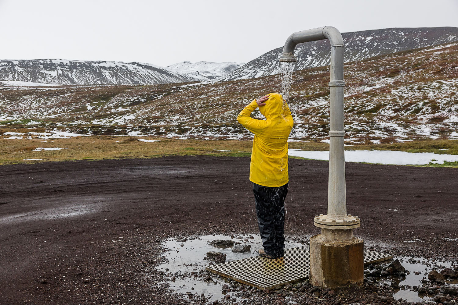 Fotografin testet heiße Außendusche im Hochthermalgebiet bei Krafla in Nordisland während einer Fotoreise
