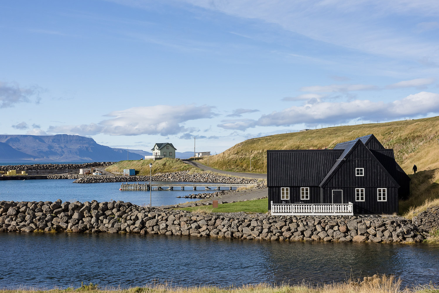 Hofsós in Nordisland – Hafen am Fjord mit schwarzem Holzhaus und Steinmauer