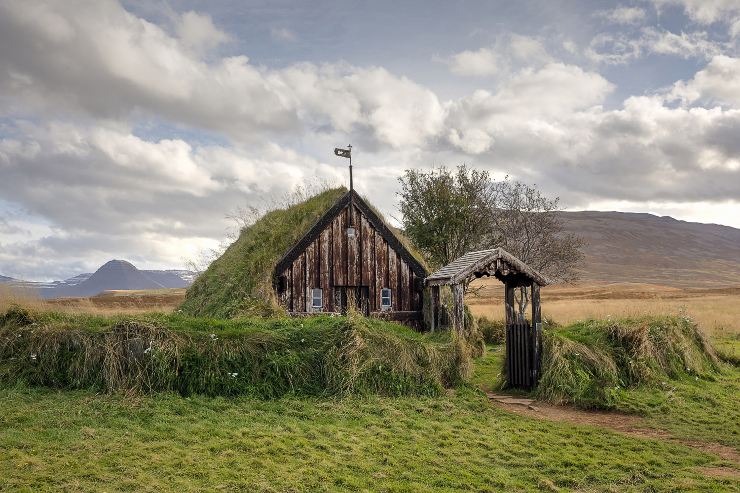 Grafarkirkja (Kirche in Gröf) bei Hofsós in Nordisland – älteste erhaltene Torfkirche Islands mit Grassodendach, Holztür und Eingangstor.