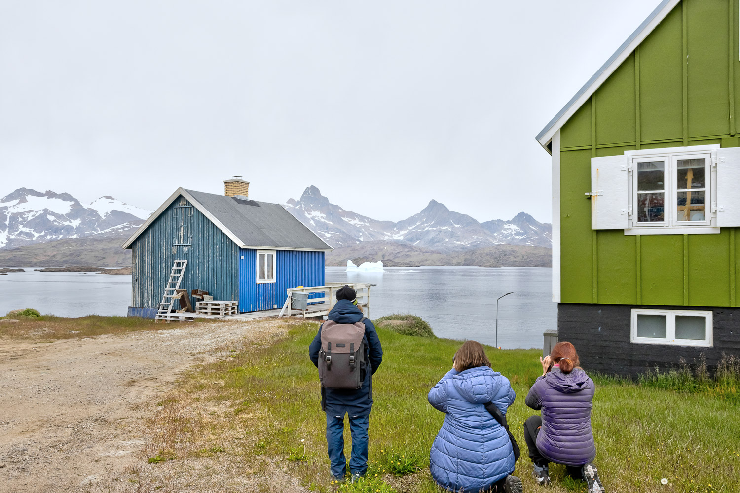 Fotografieren in einer Siedlung Ostgrönlands Teilnehmer einer Fotoreise fotografieren zwischen bunten Häusern mit Blick auf Eisberge und Berge in Ostgrönland Foto: Radmila Dier