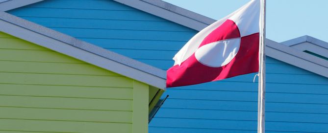 Grönländische Flagge vor bunten Holzhäusern in Grönland – Symbol für Autonomie, Identität und arktischen Lebensraum