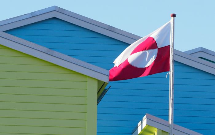 Grönländische Flagge vor bunten Holzhäusern in Grönland – Symbol für Autonomie, Identität und arktischen Lebensraum