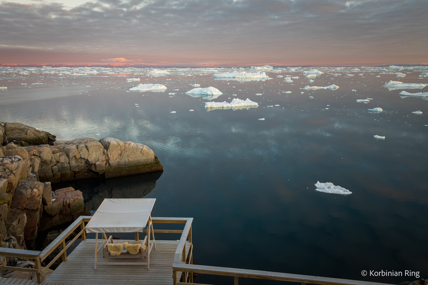 Hotelterrasse mit Schaukel und Blick auf Eisberge in der Diskobucht bei Ilulissat