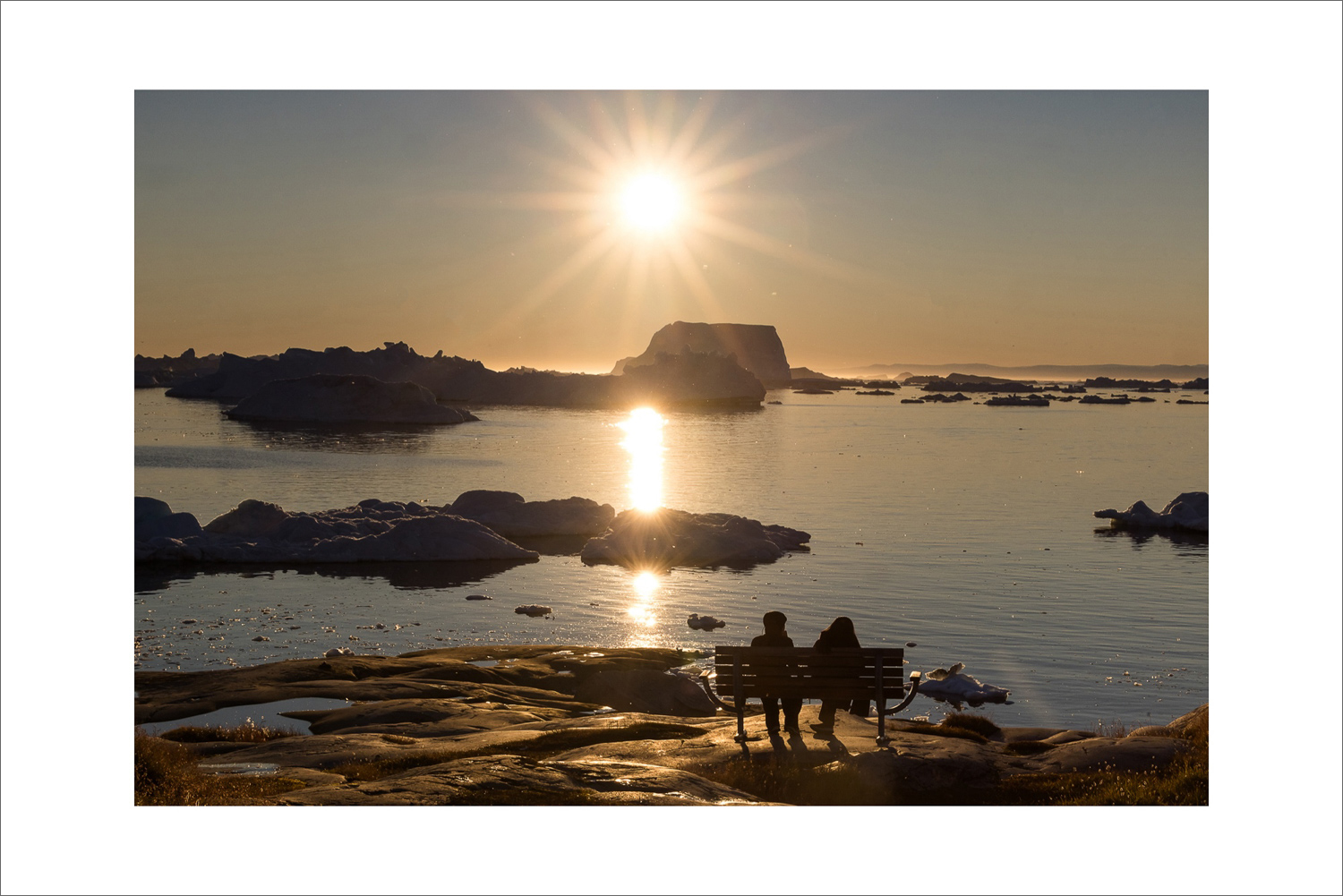 Blick von der Kirche in Ilulissat über die Diskobucht mit Eisbergen im warmen Abendlicht während einer Fotoreise nach Grönland