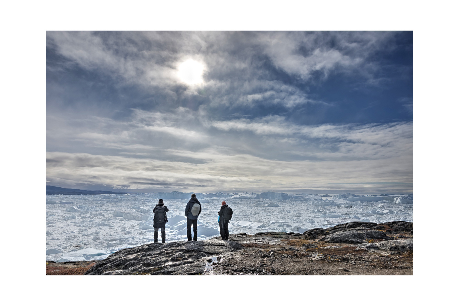 Personen stehen auf Felsen und blicken auf das Eisfeld des Ilulissat Eisfjords während einer Fotoreise nach Grönland