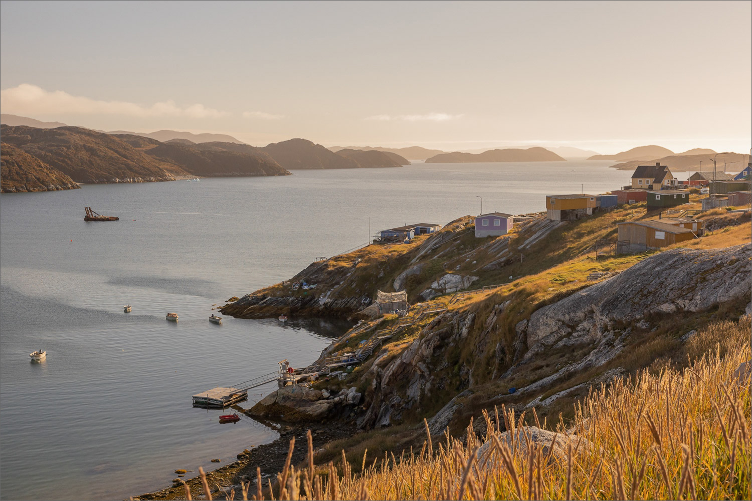 Blick über Qasigiannguit mit bunten Häusern, kleinen Booten und ruhiger Küstenlandschaft an der Diskobucht in Grönland