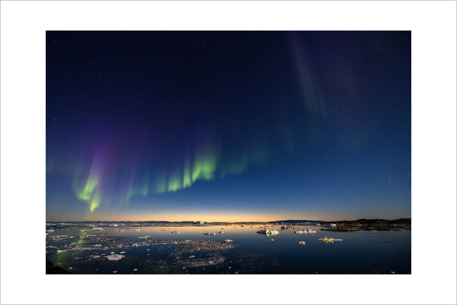 Polarlicht über der Diskobucht bei Ilulissat mit grün-violetten Nordlichtern, Sternenhimmel und treibenden Eisbergen in der arktischen Nacht Grönlands.