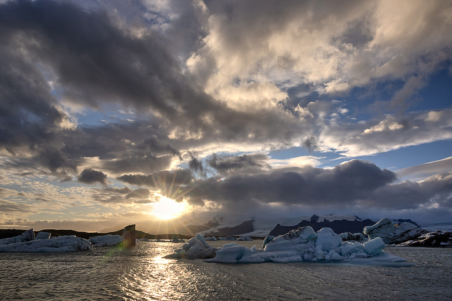Eisberge in der Gletscherlagune Jökulsárlón in Island bei dramatischem Licht und Sonnenstrahlen über dem Wasser