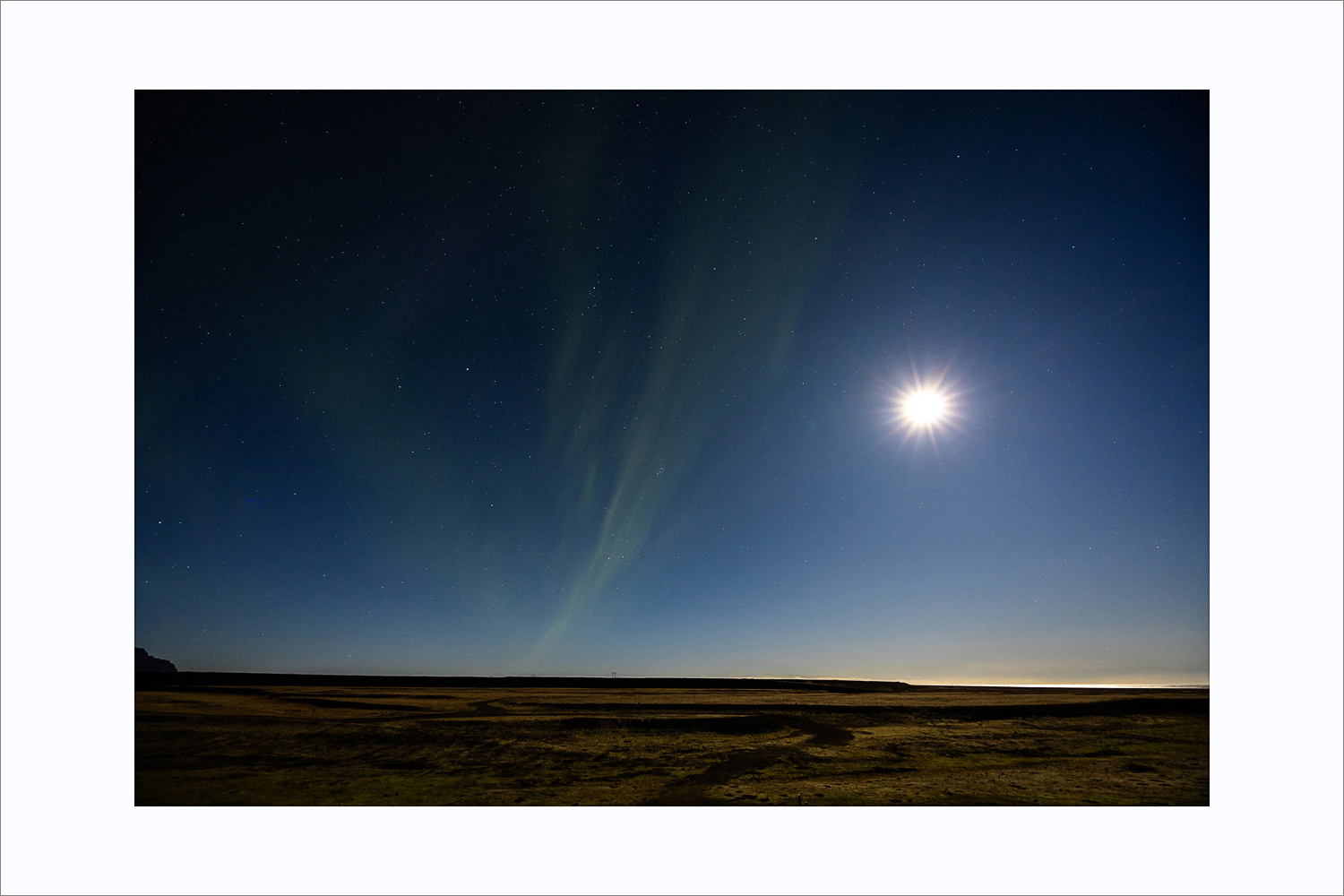 Polarlichter und Vollmond über der Landschaft im Süden Islands in klarer Nacht