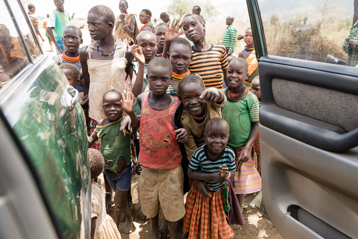 Kinder in Karamoja in Uganda begrüßen Besucher an einem Fahrzeug
