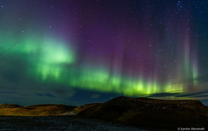 Grüne Polarlichter und Sternenhimmel über der dunklen Landschaft am Mývatn in Nordisland