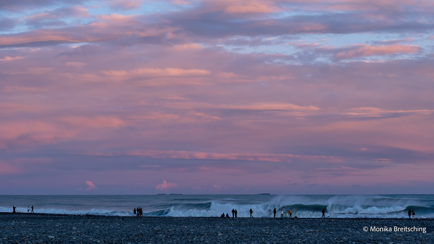 Fotografen als kleine Silhouetten vor der Brandung am schwarzen Strand Reynisfjara in Island