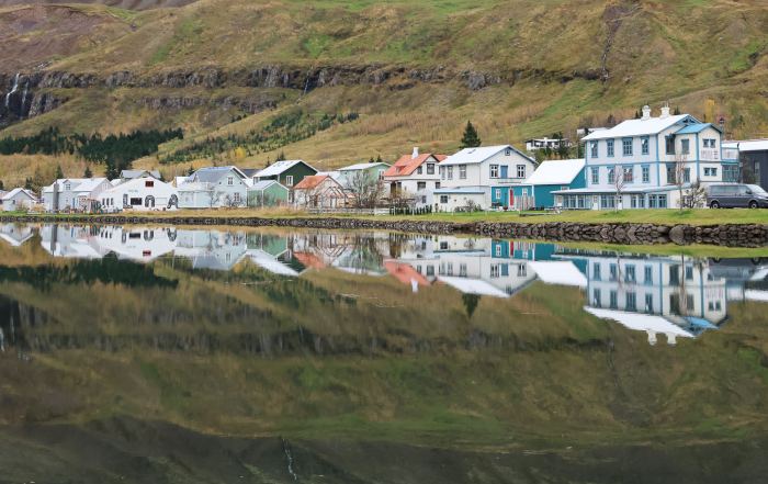 Historische Häuser von Seyðisfjörður spiegeln sich im ruhigen Wasser des Fjords im Osten Islands.