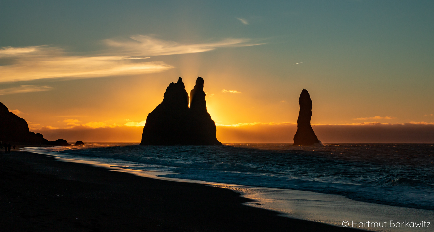Reynisdrangar-Felsnadeln als Silhouetten beim Sonnenaufgang am schwarzen Strand Reynisfjara in Island
