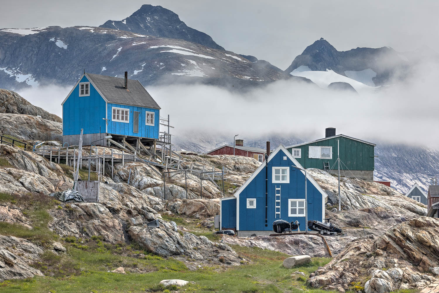 Tiniteqilaaq vor der Bergkulisse Ostgrönlands Bunte Häuser von Tiniteqilaaq vor wolkenverhangenen Bergen in Ostgrönland